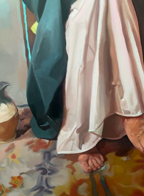 Person's foot standing on floral floor wearing white and green flowing linens.